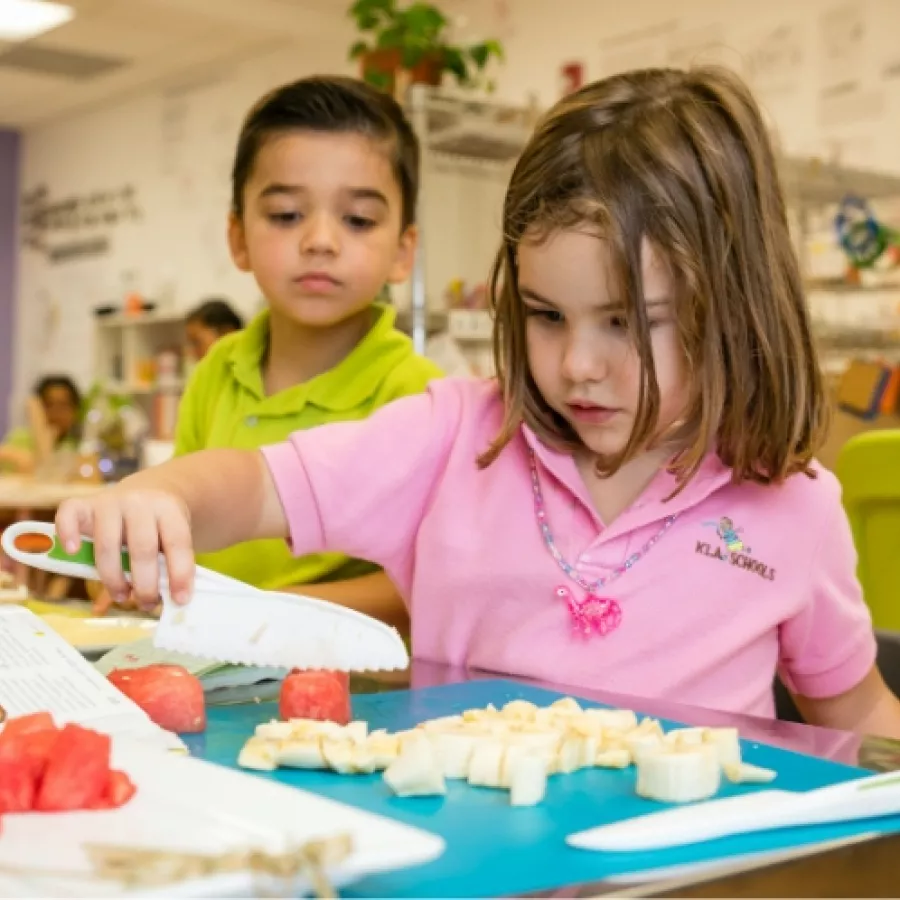 a girl student cutting watermelon in a cooking class at our preschool in Aventura, Florida