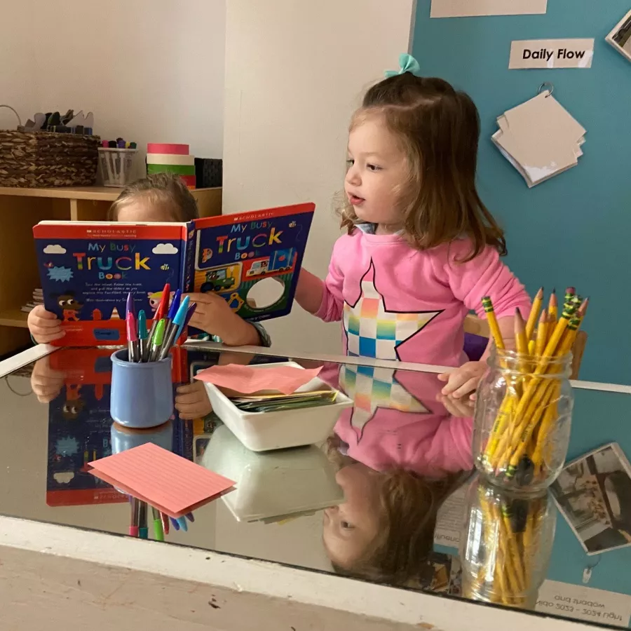 Children reading a book together at our Coral Gables daycare