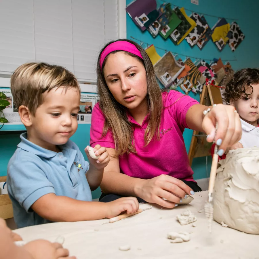 a group of toddlers and teacher playing with clay in our toddler preschool