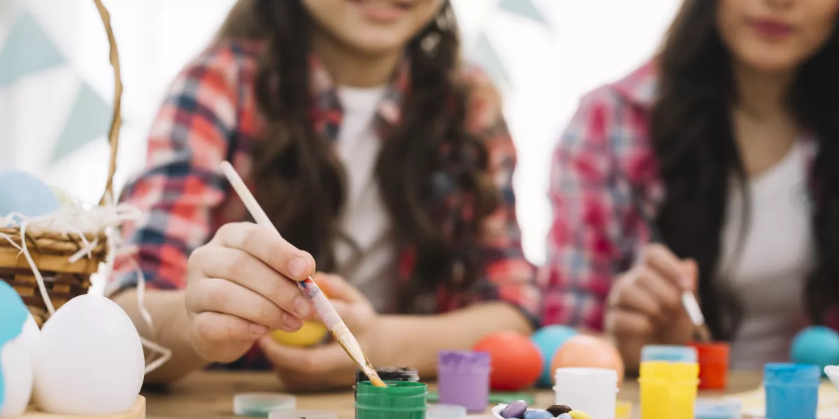 Blurred mother daughter painting easter eggs table