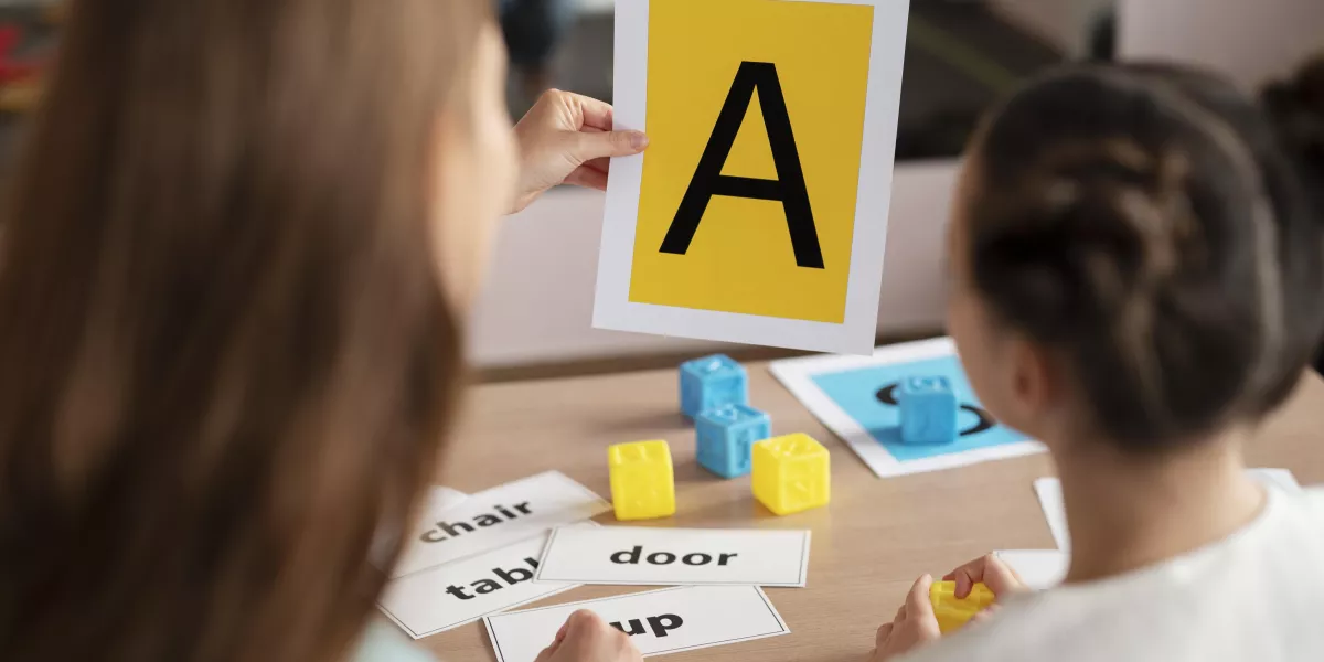 Psychologist helping little girl speech therapy indoors
