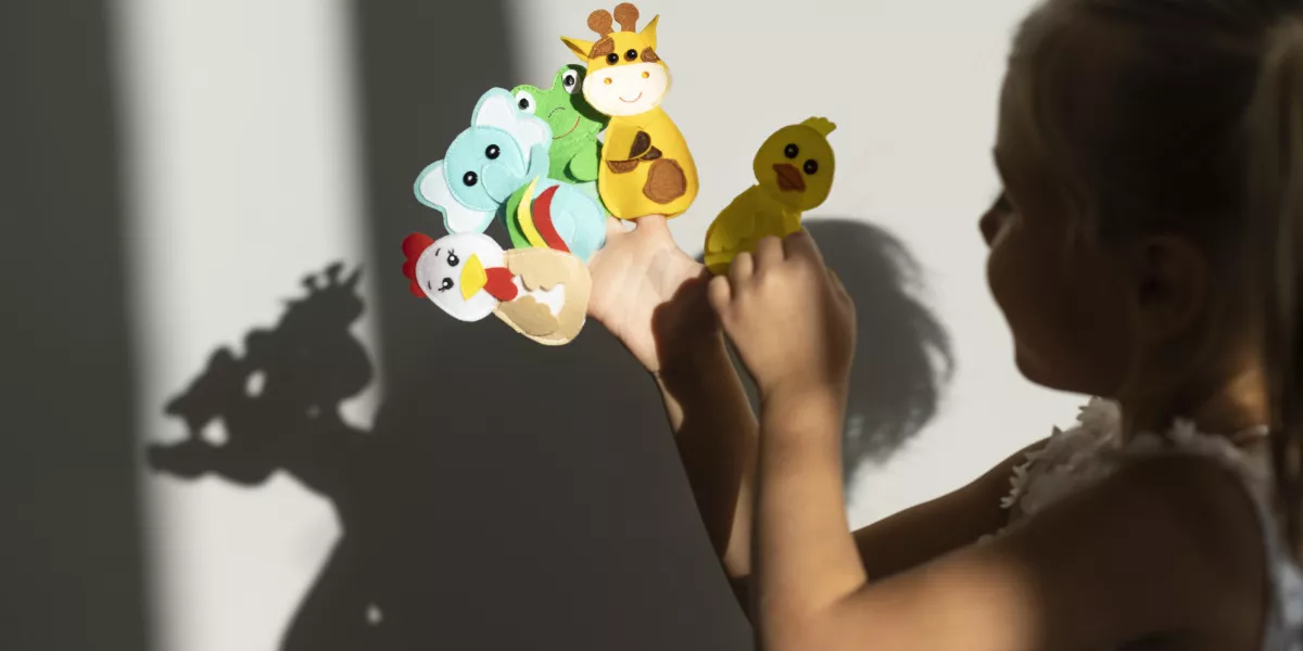 Adorable little girl playing with her puppets home