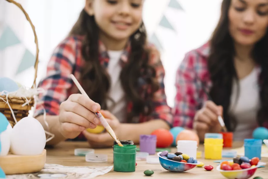 Blurred mother daughter painting easter eggs table