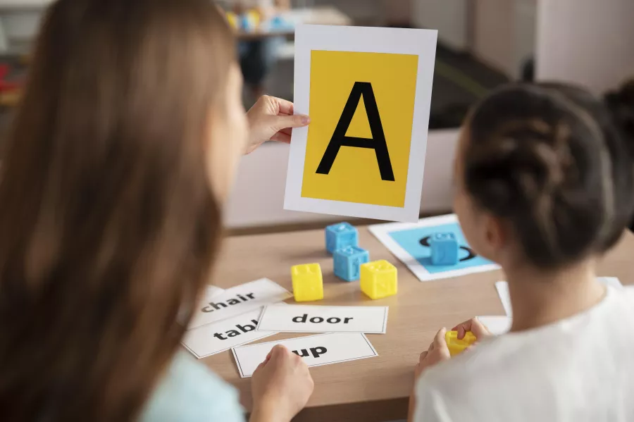 Psychologist helping little girl speech therapy indoors