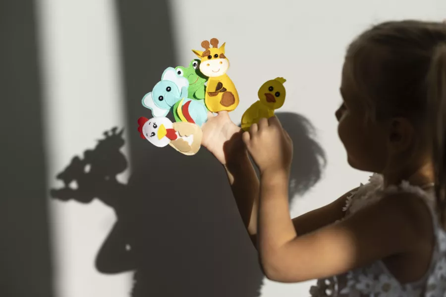 Adorable little girl playing with her puppets home