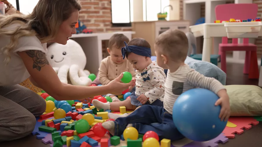 Teacher preschool students playing with balls sitting floor kindergarten