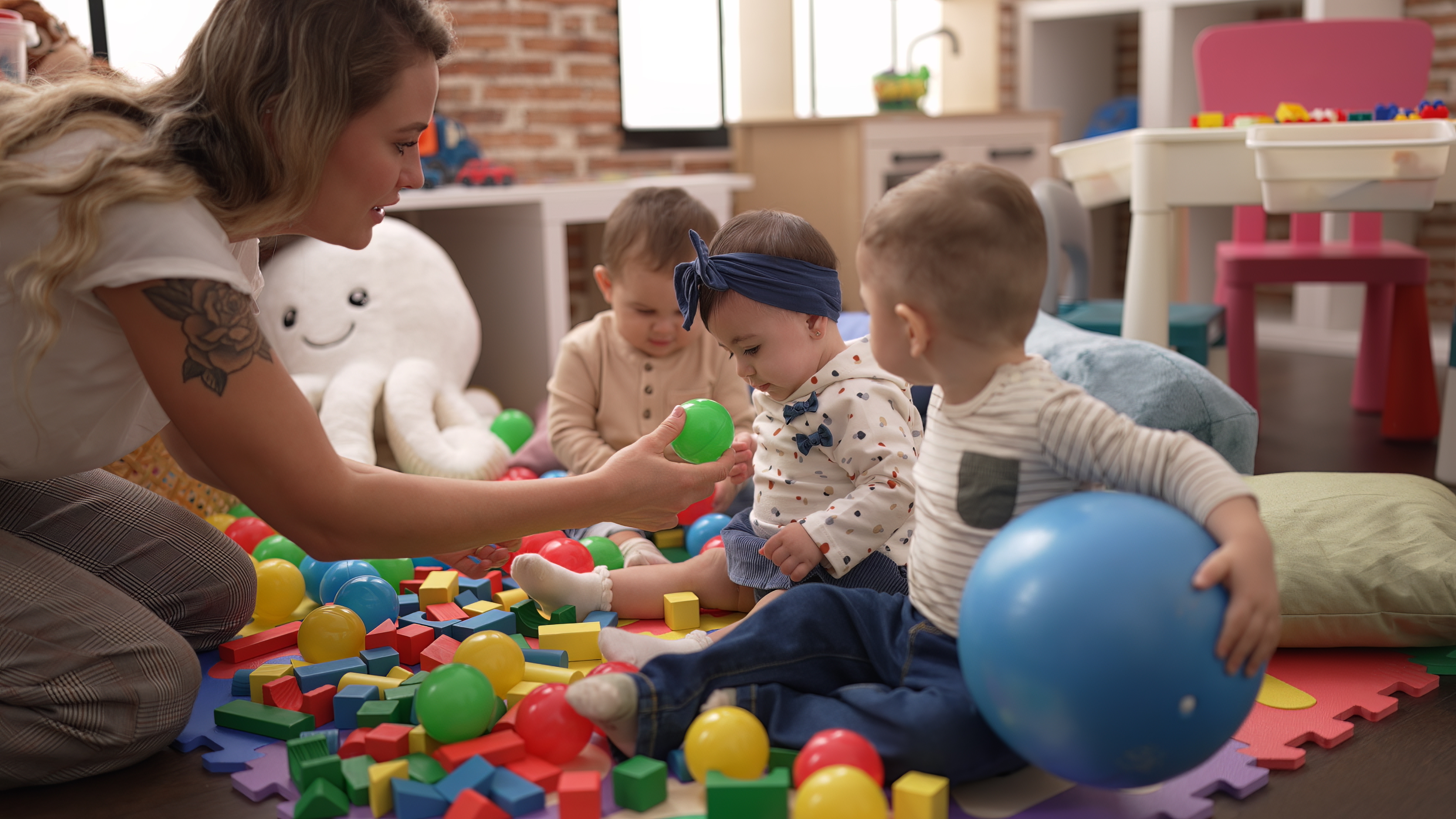 Teacher preschool students playing with balls sitting floor kindergarten