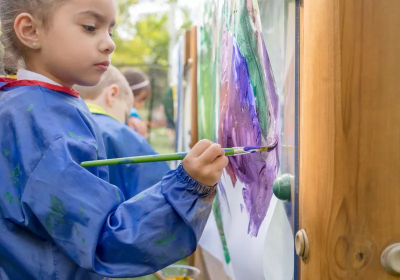 Preschooler painting outside