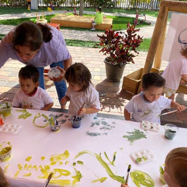 Toddlers painting outside and teacher