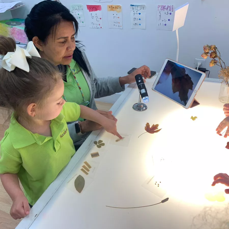 Girls and teacher in light table with Ipad and plants