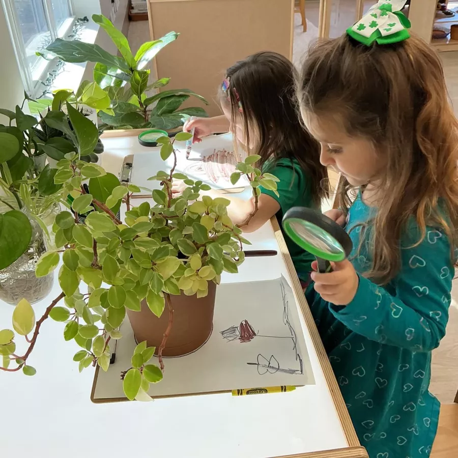Girl with magnifying glass looking at plants KLA Wallingford