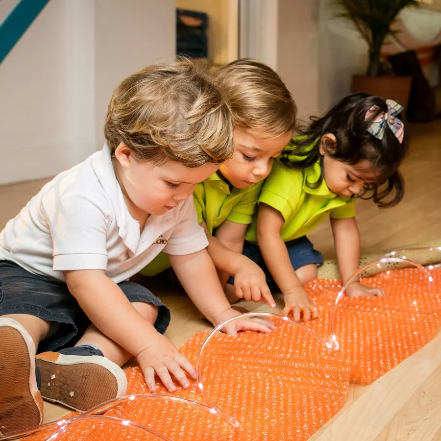 three toddler children playing with lights in our toddler program
